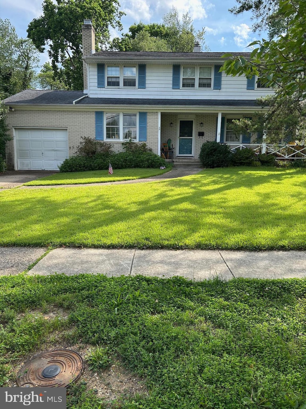 212 Walt Whitman Blvd, Cherry Hill, NJ 08003 - traditional home with a chimney, a garage, a front lawn, brick siding, and a porch