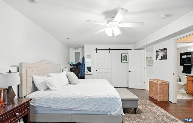 106 Alex Dr, Madison Heights, VA 24572 - bedroom with a barn door, dark wood-style floors, a ceiling fan, and connected bathroom