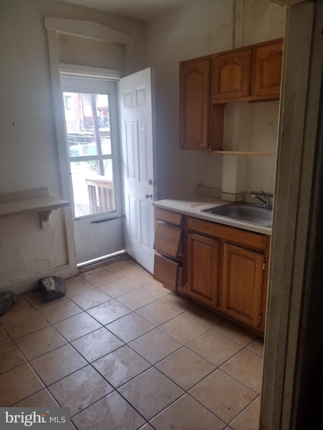 2714 E Biddle St, Baltimore, MD 21213 - kitchen with light tile patterned floors, light countertops, and brown cabinetry
