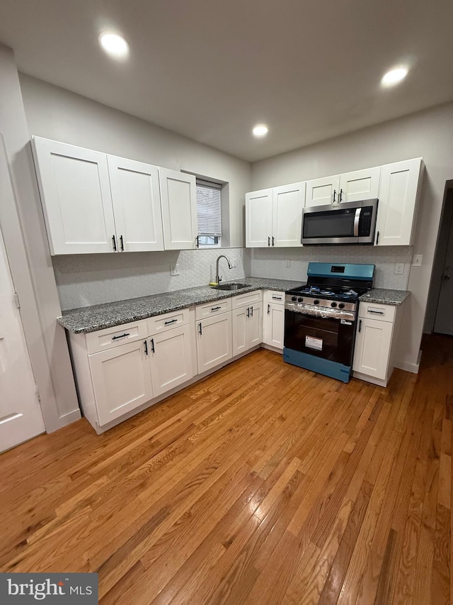 3844 N Franklin St, Philadelphia, PA 19140 - kitchen featuring appliances with stainless steel finishes, white cabinets, light wood-style floors, stone countertops, and tasteful backsplash