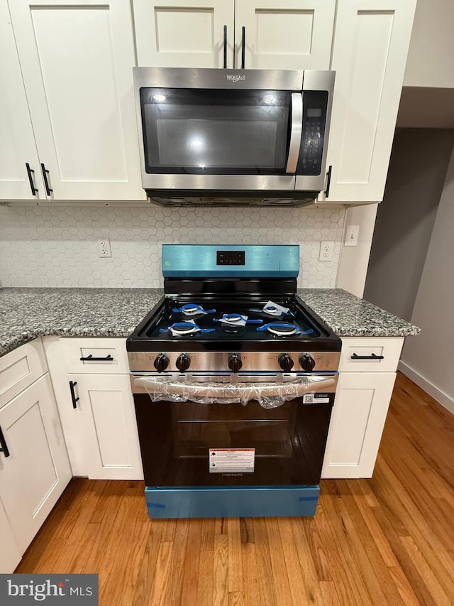 3844 N Franklin St, Philadelphia, PA 19140 - kitchen featuring appliances with stainless steel finishes, light wood-style floors, white cabinets, and dark stone countertops