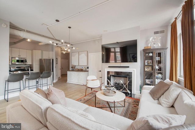4480 Market Commons Dr Unit 215, Fairfax, VA 22033 - living room featuring light wood-style floors, a chandelier, and a tile fireplace