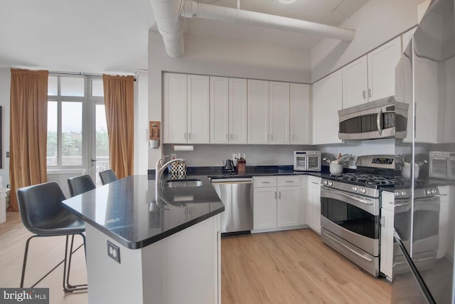 4480 Market Commons Dr Unit 215, Fairfax, VA 22033 - kitchen featuring stainless steel appliances, a peninsula, light wood finished floors, and white cabinetry