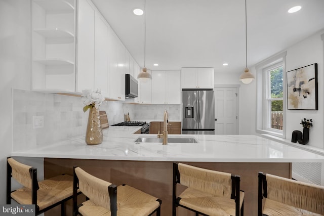 136 W 3rd Ave, Conshohocken, PA 19428 - kitchen with stainless steel appliances, a peninsula, decorative backsplash, decorative light fixtures, and light stone countertops