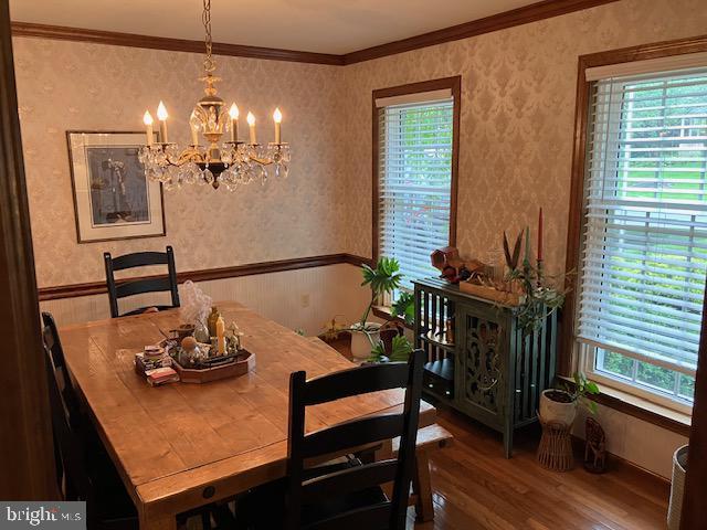 409 Rhoda Dr, Lancaster, PA 17601 - dining area featuring wallpapered walls, a chandelier, wood finished floors, plenty of natural light, and ornamental molding