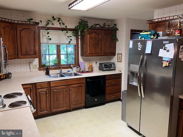 409 Rhoda Dr, Lancaster, PA 17601 - kitchen with stainless steel fridge with ice dispenser, dishwasher, wallpapered walls, light countertops, and light floors