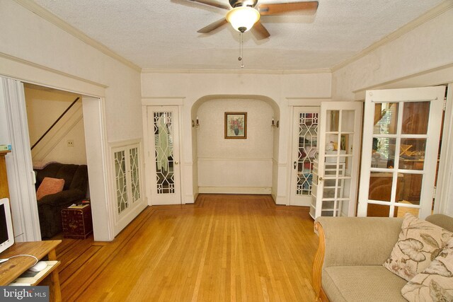 4425 E Howell St, Philadelphia, PA 19135 - unfurnished living room featuring a textured ceiling, light wood finished floors, ceiling fan, arched walkways, and crown molding
