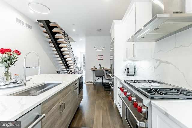 1217 Bainbridge St, Philadelphia, PA 19147 - kitchen featuring wall chimney exhaust hood, appliances with stainless steel finishes, dark wood-style floors, white cabinets, and light stone countertops