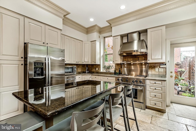 2101 Wallace St, Philadelphia, PA 19130 - kitchen with appliances with stainless steel finishes, wall chimney exhaust hood, crown molding, healthy amount of natural light, and a breakfast bar area