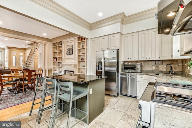 2101 Wallace St, Philadelphia, PA 19130 - kitchen with stainless steel appliances, crown molding, extractor fan, dark stone counters, and a kitchen island