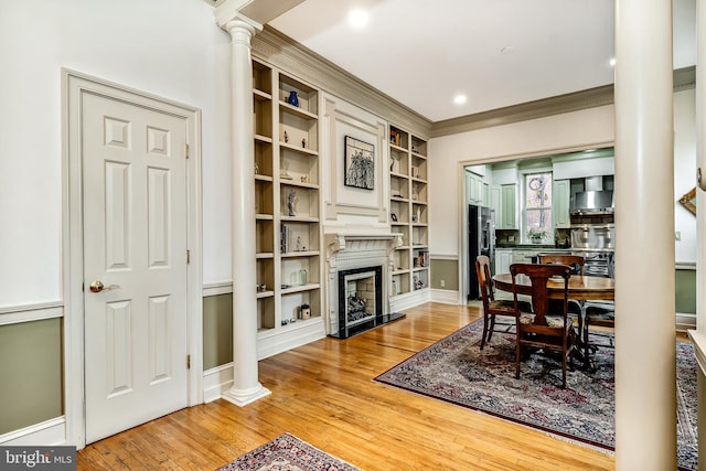 2101 Wallace St, Philadelphia, PA 19130 - dining space with decorative columns, light wood-style floors, ornamental molding, a fireplace, and built in shelves