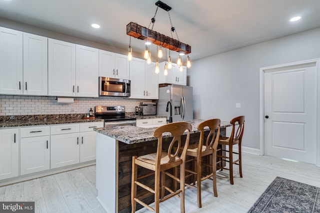 15065 Rock Point Rd, Newburg, MD 20664 - kitchen featuring appliances with stainless steel finishes, decorative backsplash, a breakfast bar area, dark stone countertops, and a center island with sink