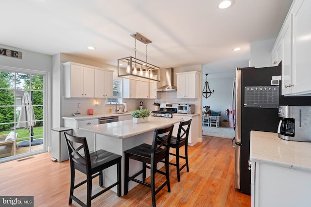 136 Tiller Ave, Manahawkin, NJ 08050 - kitchen with wall chimney range hood, appliances with stainless steel finishes, white cabinetry, plenty of natural light, and recessed lighting