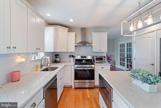 136 Tiller Ave, Manahawkin, NJ 08050 - kitchen featuring appliances with stainless steel finishes, wall chimney exhaust hood, light wood-type flooring, white cabinets, and recessed lighting