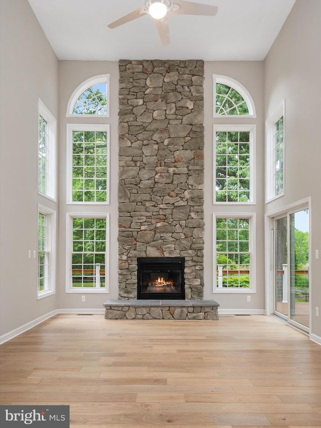 1015 S Creek View Ct, Churchton, MD 20733 - unfurnished living room featuring a towering ceiling, ceiling fan, plenty of natural light, a stone fireplace, and wood finished floors