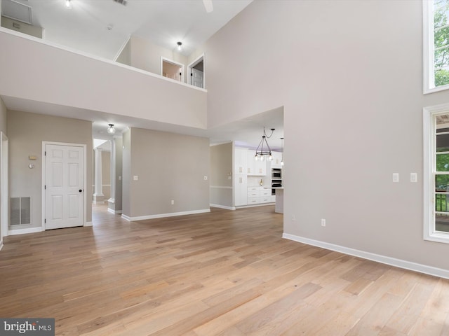 1015 S Creek View Ct, Churchton, MD 20733 - unfurnished living room featuring a towering ceiling, ornate columns, light wood-style flooring, and healthy amount of natural light