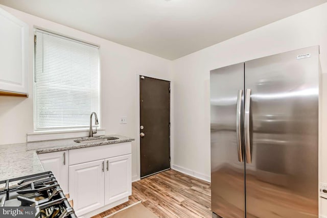 2750 N 28th St, Philadelphia, PA 19132 - kitchen featuring freestanding refrigerator, light wood-type flooring, white cabinets, light stone countertops, and stove