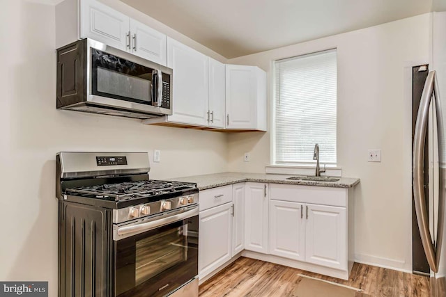 2750 N 28th St, Philadelphia, PA 19132 - kitchen featuring stainless steel appliances, white cabinets, light wood-style floors, and light stone countertops