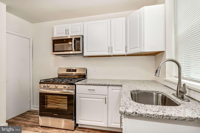 2750 N 28th St, Philadelphia, PA 19132 - kitchen with appliances with stainless steel finishes, white cabinets, light wood-style flooring, and light stone counters
