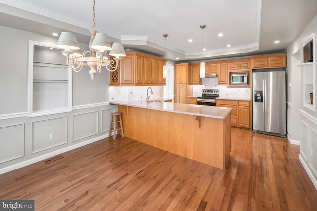 51 E Ann Rd, Broomall, PA 19008 - kitchen with appliances with stainless steel finishes, a chandelier, a decorative wall, a peninsula, and light wood-style flooring