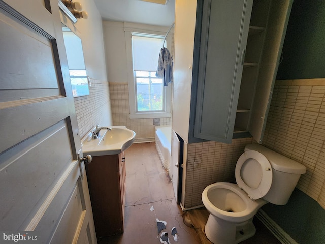 3137 Oakford Ave, Baltimore, MD 21215 - bathroom featuring tile walls, vanity, a tub to relax in, and wainscoting
