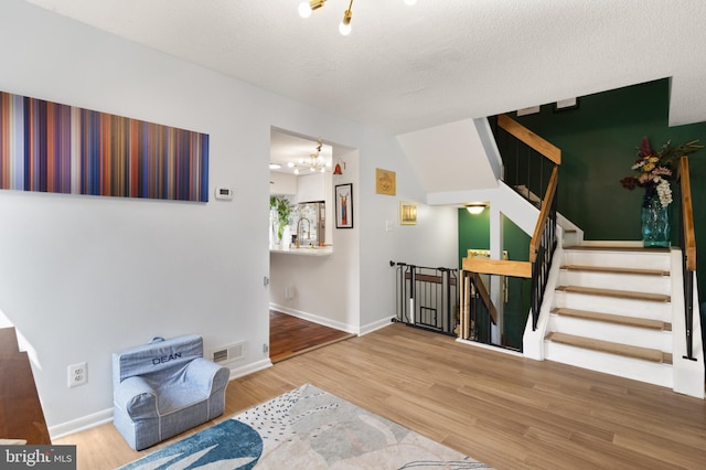 3086 Bridgeton Ct, Woodbridge, VA 22192 - living area featuring wood finished floors, a chandelier, stairs, and a textured ceiling