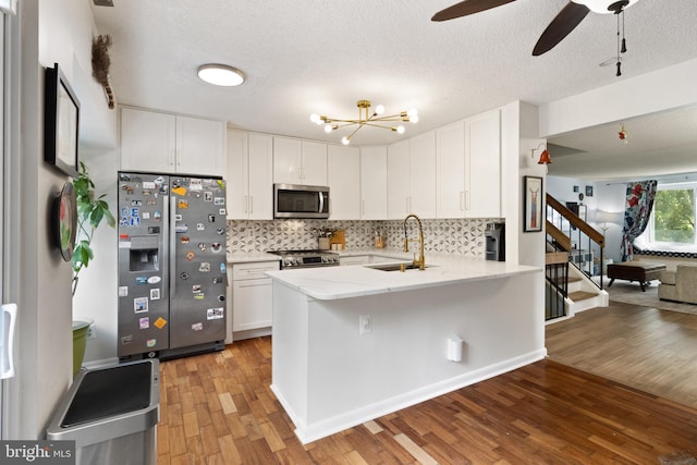 3086 Bridgeton Ct, Woodbridge, VA 22192 - kitchen with appliances with stainless steel finishes, light wood finished floors, a peninsula, white cabinets, and a textured ceiling