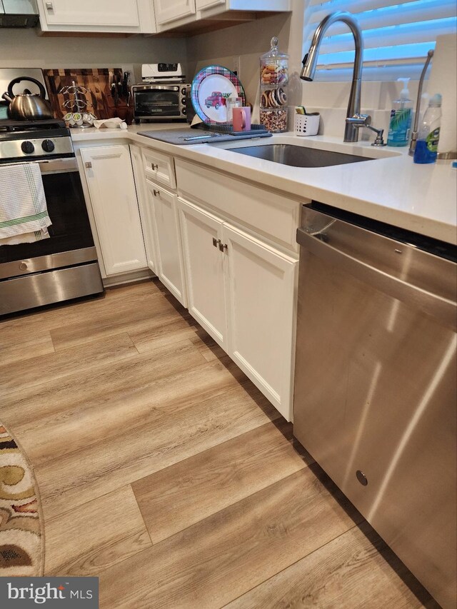 100 Senators Way, Berlin, NJ 08009 - kitchen featuring stainless steel appliances, light countertops, white cabinets, light wood-style floors, and exhaust hood