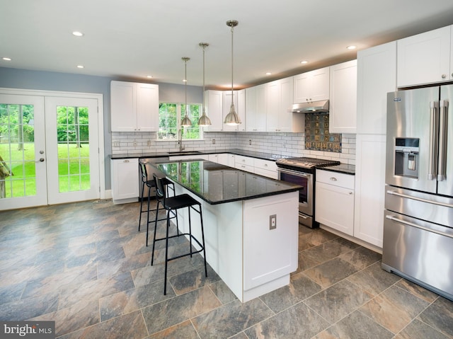 319 W Conestoga Rd, Devon, PA 19333 - kitchen with appliances with stainless steel finishes, dark stone finish flooring, a breakfast bar area, tasteful backsplash, and white cabinets