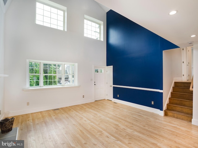 319 W Conestoga Rd, Devon, PA 19333 - unfurnished living room with wood finished floors, healthy amount of natural light, stairs, a towering ceiling, and recessed lighting