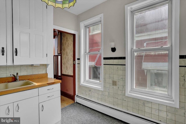 1243 Buttonwood St, Reading, PA 19604 - kitchen featuring a baseboard heating unit, wainscoting, white cabinets, and light countertops