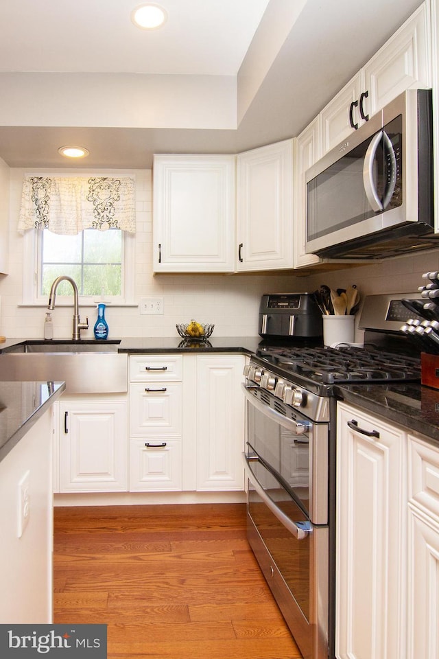 5997 Florey Rd, Hanover, MD 21076 - kitchen featuring appliances with stainless steel finishes, white cabinetry, recessed lighting, light wood-type flooring, and backsplash