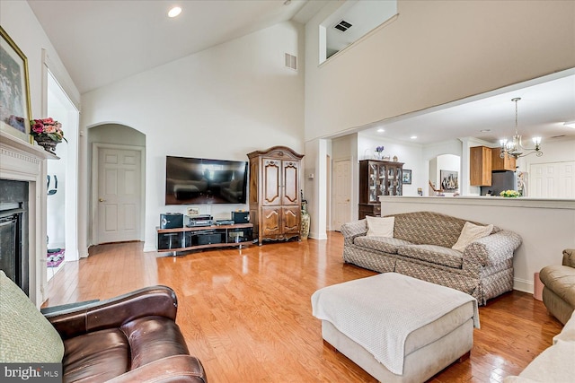 16 Monte Carlo Dr, Hamilton, NJ 08691 - living room with arched walkways, a chandelier, a glass covered fireplace, high vaulted ceiling, and wood finished floors