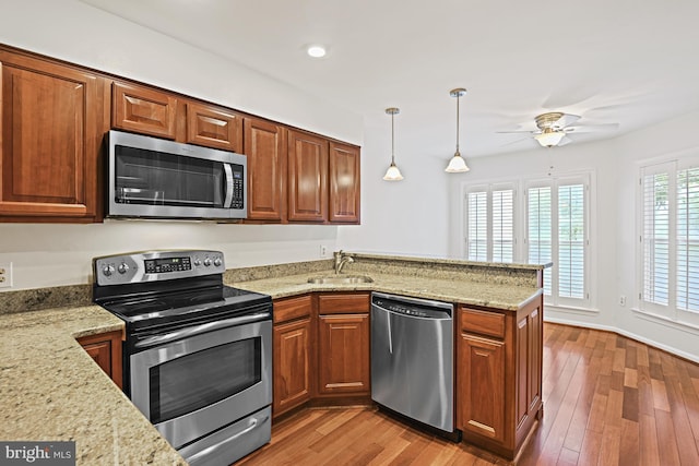 9405 Odyssey Ct, Burke, VA 22015 - kitchen featuring appliances with stainless steel finishes, a peninsula, a ceiling fan, light stone countertops, and wood finished floors