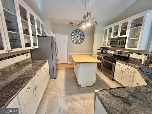61 Kirby Ln, Stafford, VA 22554 - kitchen with stainless steel appliances, a kitchen island, dark stone counters, white cabinetry, and vaulted ceiling