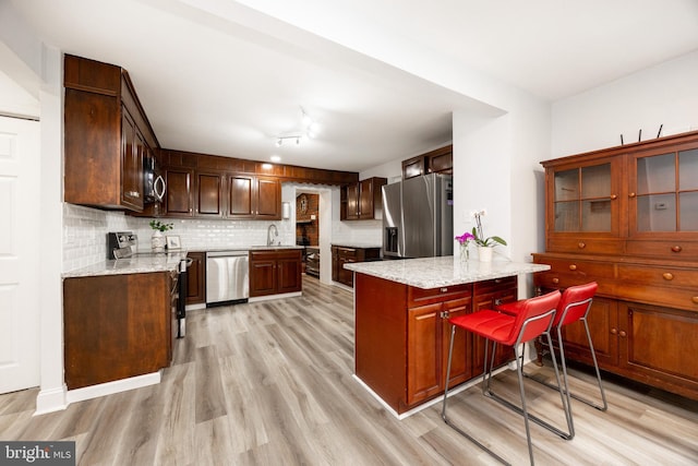 661 Schoolside Ln, Swarthmore, PA 19081 - kitchen with stainless steel appliances, light wood-style flooring, decorative backsplash, and light stone counters