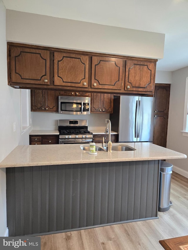 7512 Valley Ave, Philadelphia, PA 19128 - kitchen featuring appliances with stainless steel finishes, light wood-type flooring, light stone countertops, and a peninsula