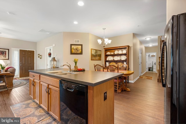 1080 Arbour Ln, Quakertown, PA 18951 - kitchen with black appliances, a chandelier, wood finished floors, dark countertops, and a center island with sink