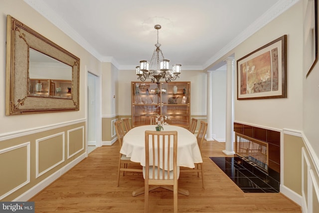 8162 Madrillon Ct, Vienna, VA 22182 - dining area featuring a chandelier, wood finished floors, decorative columns, crown molding, and a wainscoted wall