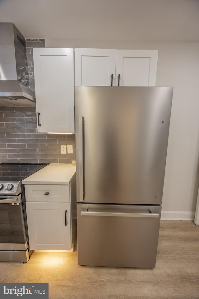 7127 Woolston Ave, Philadelphia, PA 19138 - kitchen featuring appliances with stainless steel finishes, wall chimney range hood, white cabinets, and tasteful backsplash