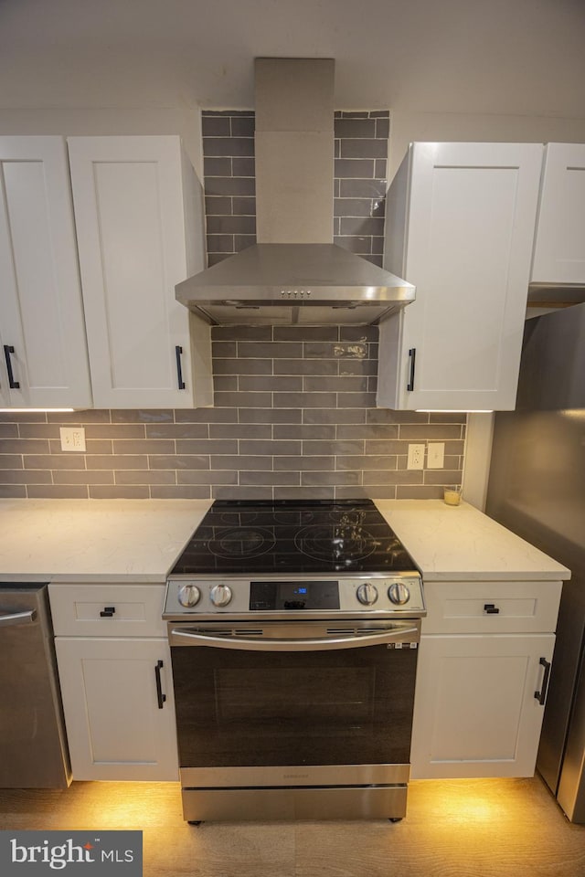 7127 Woolston Ave, Philadelphia, PA 19138 - kitchen with appliances with stainless steel finishes, wall chimney range hood, white cabinetry, light stone countertops, and decorative backsplash