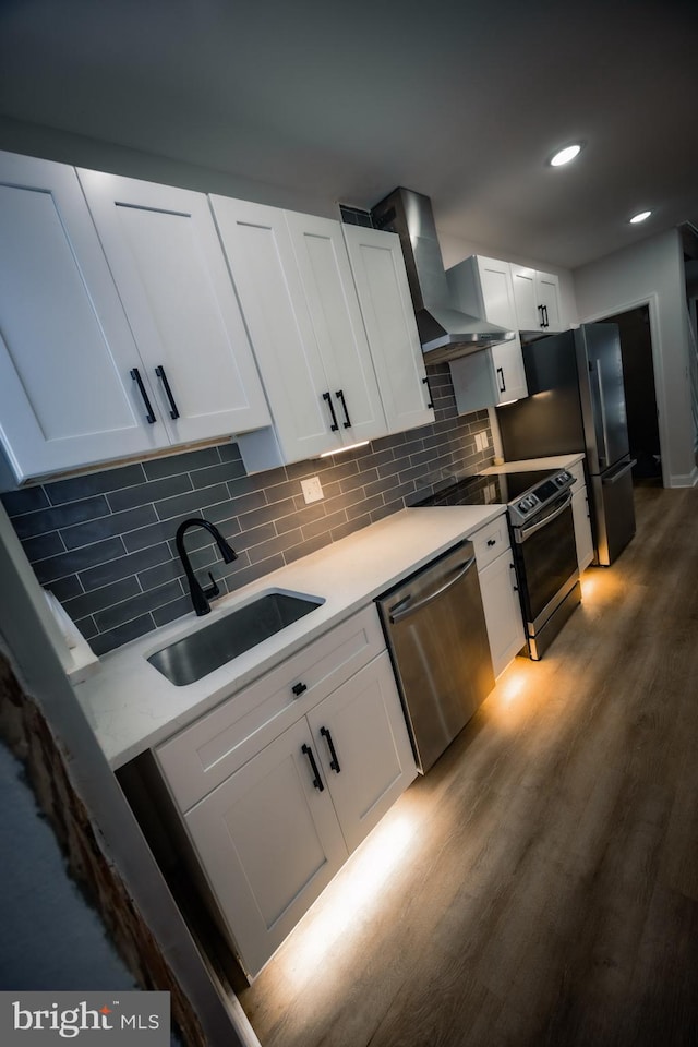 7127 Woolston Ave, Philadelphia, PA 19138 - kitchen featuring stainless steel appliances, wall chimney exhaust hood, light countertops, dark wood-type flooring, and white cabinetry