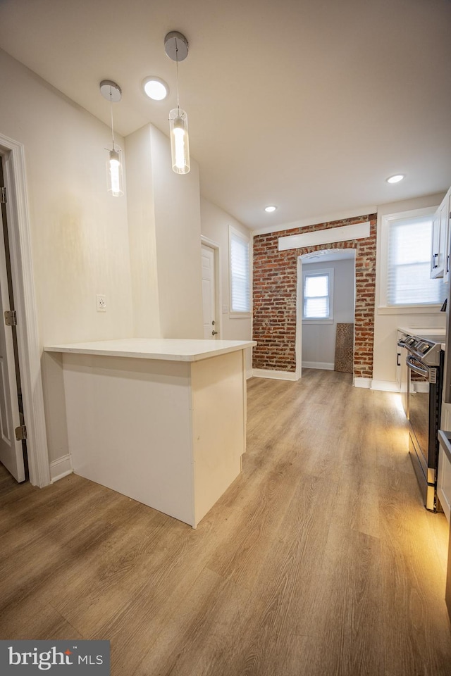 7127 Woolston Ave, Philadelphia, PA 19138 - bar with stainless steel electric stove, light wood-style floors, decorative light fixtures, and brick wall