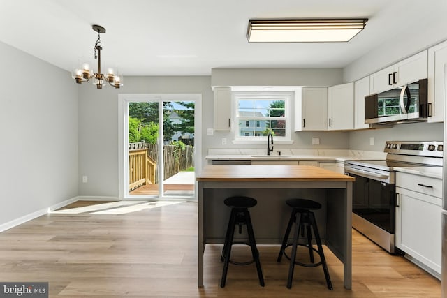 3159 Benton Square Dr, Olney, MD 20832 - kitchen featuring stainless steel appliances, butcher block countertops, a kitchen bar, white cabinetry, and light wood finished floors