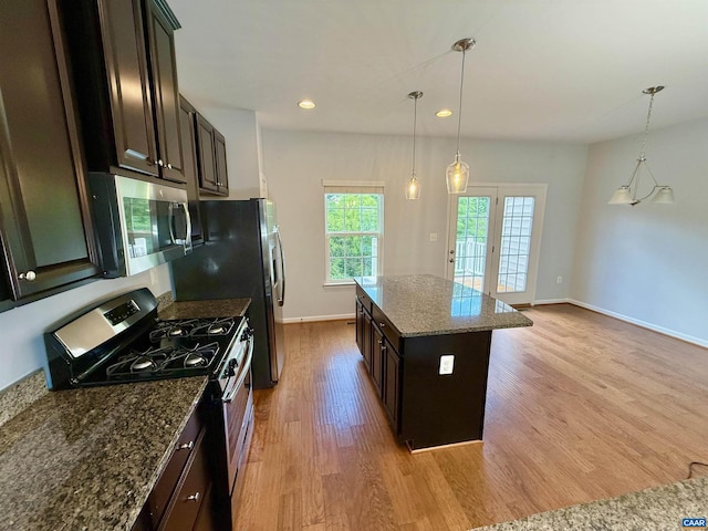 2176 Whispering Hollow Ln, Charlottesville, VA 22911 - kitchen with appliances with stainless steel finishes, light wood-style flooring, a center island, dark stone countertops, and hanging light fixtures