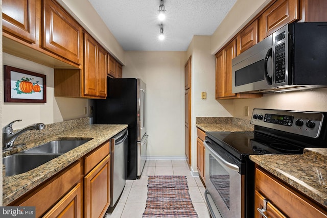 1533 Lincoln Way Unit 301A, Mclean, VA 22102 - kitchen with stainless steel appliances, brown cabinetry, light stone counters, light tile patterned floors, and a textured ceiling
