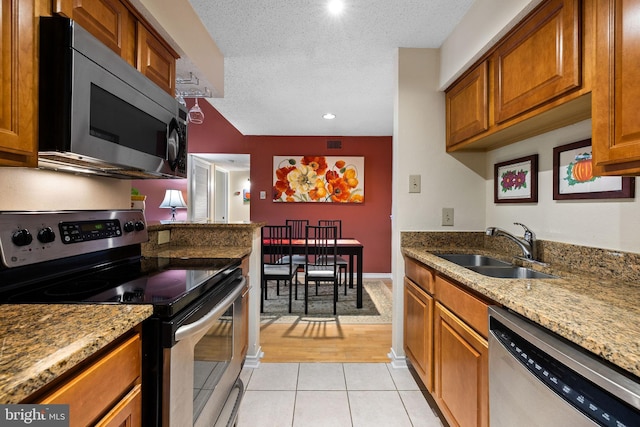 1533 Lincoln Way Unit 301A, Mclean, VA 22102 - kitchen with stainless steel appliances, brown cabinets, light tile patterned floors, light stone counters, and a textured ceiling