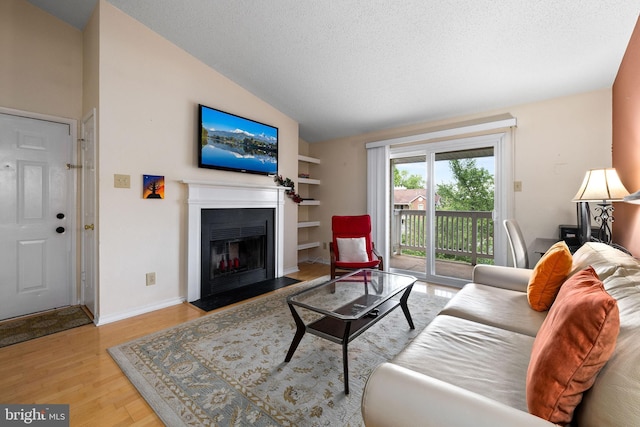 1533 Lincoln Way Unit 301A, Mclean, VA 22102 - living room featuring a fireplace with flush hearth, wood finished floors, lofted ceiling, a textured ceiling, and built in shelves