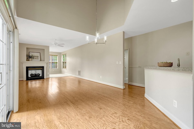 13854 Cinch Ln, Gainesville, VA 20155 - unfurnished living room featuring light wood finished floors, a multi sided fireplace, a chandelier, and ceiling fan
