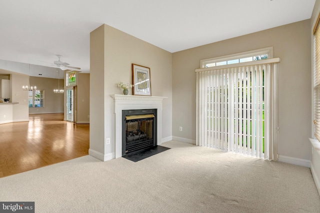 13854 Cinch Ln, Gainesville, VA 20155 - unfurnished living room featuring a fireplace with flush hearth, ceiling fan, carpet flooring, a chandelier, and wood finished floors